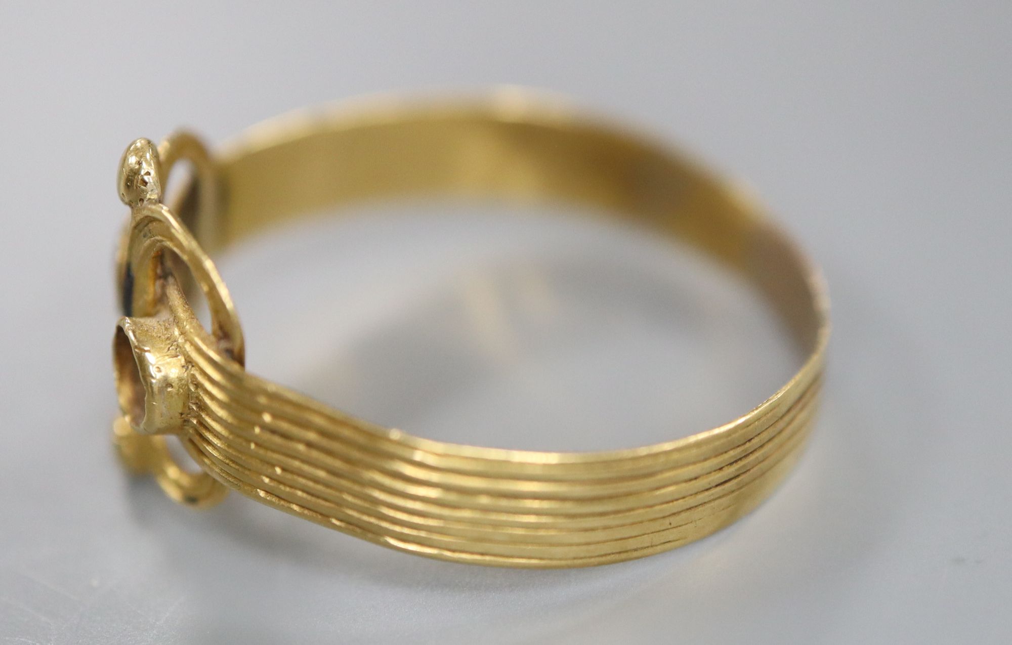 An antique reeded yellow metal and two stone set scroll ring, (stone missing and other stone chipped), size R/S, gross 1.6 grams.